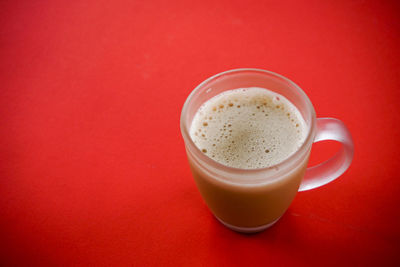 Close-up of coffee cup on table against red background