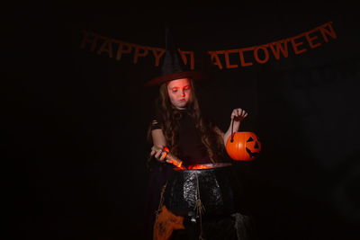 Close-up of woman holding light painting against black background