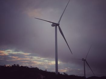 Low angle view of wind turbine against cloudy sky