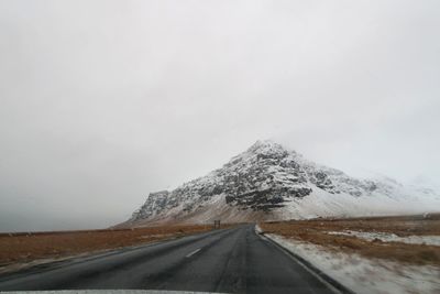 Road by snowcapped mountain against sky