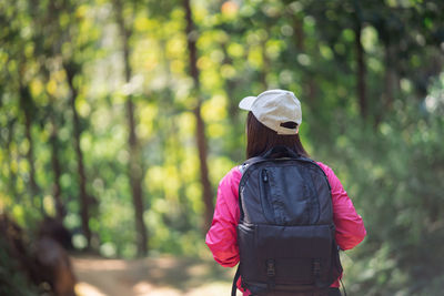 Rear view of woman standing against trees in forest