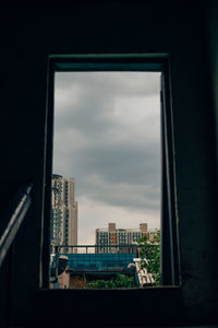 Buildings against sky seen through window