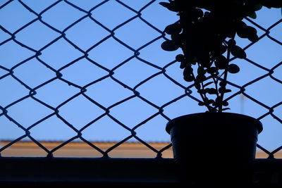 Low angle view of chainlink fence against sky during sunset