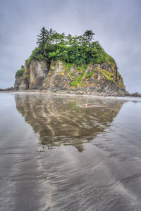 Scenic view of rocks by sea against sky
