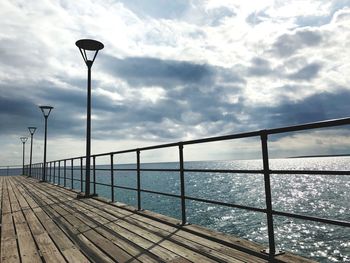 Street light by sea against sky