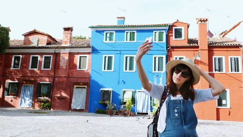 Burano island with multicolor houses near venice. tourist, young woman, girl in sun glasses, hat