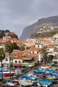 Sailboats moored at harbor by buildings in city against sky