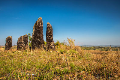 Standing sacred stone monoliths with bright blue sky and grass from a different perspective