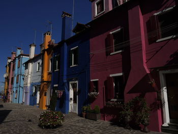 Residential buildings by street against sky