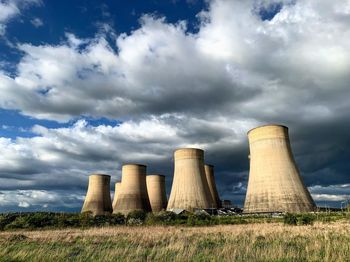 View of smoke stacks against cloudy sky