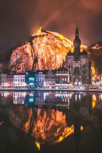 Buildings against illuminated mountain at night