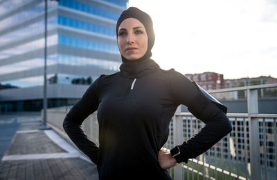 Beautiful woman wearing hijab standing against building during sunrise