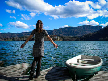 Rear view of woman looking at lake against mountain range