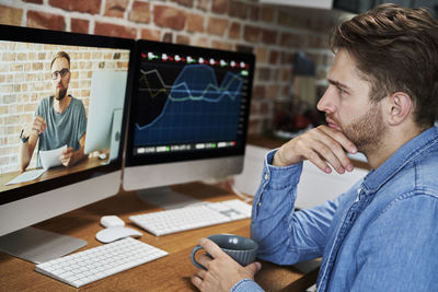 Side view of young man using laptop at office