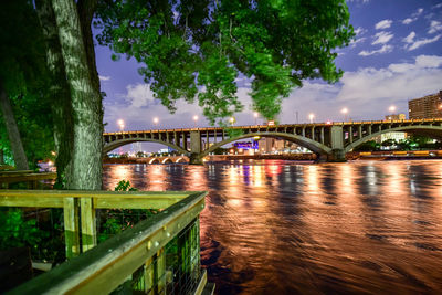 Bridge over river in city against sky at night