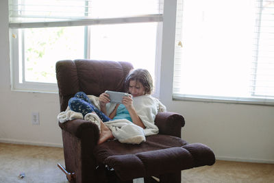 Teen girl on a recliner plays video games on her hand held device