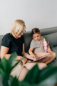 Young woman using laptop while sitting on sofa at home