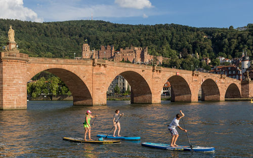 People on bridge over river against trees