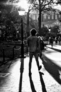 Rear view of man walking on sidewalk in city