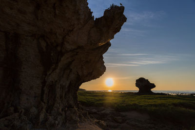 Scenic view of rock formation amidst sea against sky during sunset