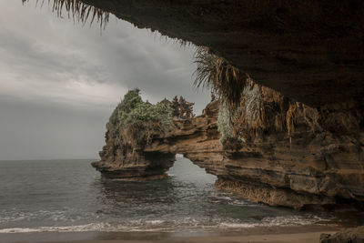 Rock formation in sea against sky