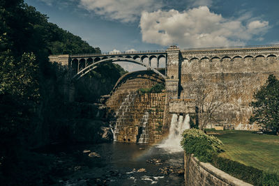 Arch bridge over river against sky