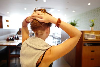 Rear view of young woman with hands behind head at restaurant