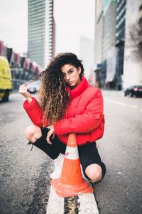 Portrait of young woman standing on wall in city