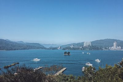 Sailboats in sea against clear blue sky