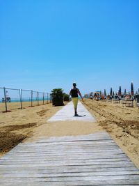 Rear view of man on beach against clear sky