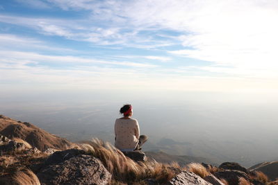 Rear view of woman sitting on mountain