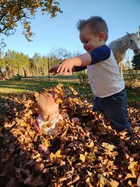 Boy and leaves on road during autumn