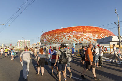 Rear view of people walking on road in city against sky