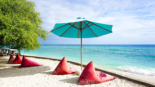 Deck chairs on beach against sky