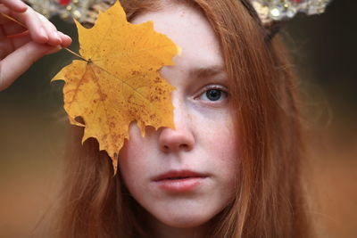 Close-up portrait of teenage girl holding autumn leaf