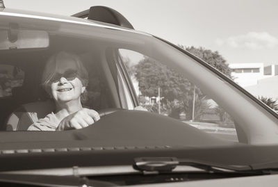 Portrait of senior woman driving car seen through windshield
