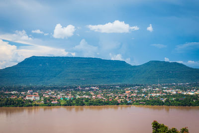 Aerial view of townscape by mountain against sky