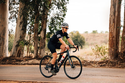 Full length of woman cycling on road