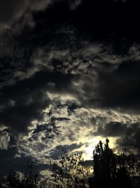 Low angle view of silhouette trees against dramatic sky