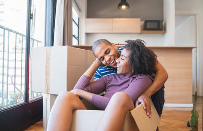 Cheerful couple having fun while sitting in new house