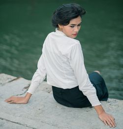 Young woman sitting by lake