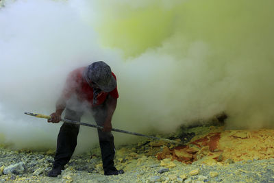 Sulfur miner in ijen crater who mine manually without being equipped with standard safety equipment