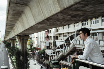 Side view of young man sitting on railing