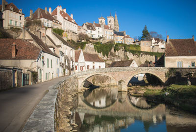 Arch bridge over river amidst buildings in town