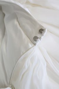 Detail of a wedding dress made of satin. a full cut skirt, a belt with a zipper drape and hooks. 