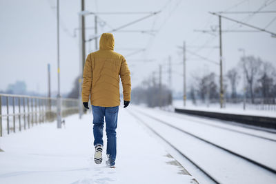 Rear view of person standing on railroad track during winter