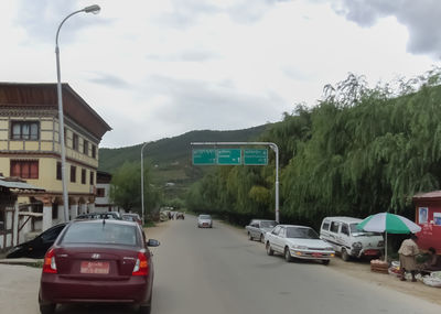 Cars on city street against sky