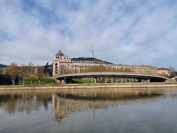 Arch bridge over river against buildings