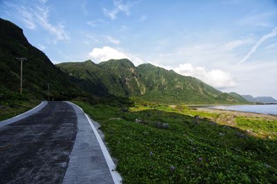 Road amidst green landscape against sky