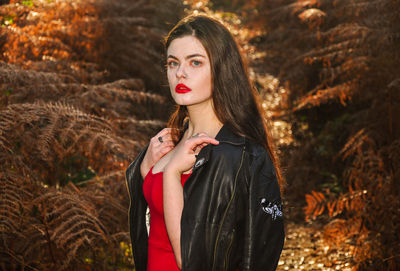 Young woman standing by tree